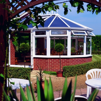 Sunny conservatory with plants and white plastic chairs
