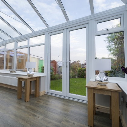 Inside view of a white conservatory with wooden furniture