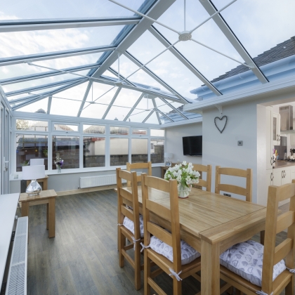 Inside view of a conservatory with wooden furniture  and glass roof