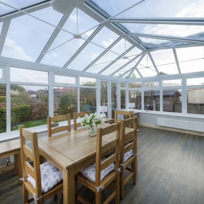 Inside view of a conservatory with wooden furniture  and sunny garden