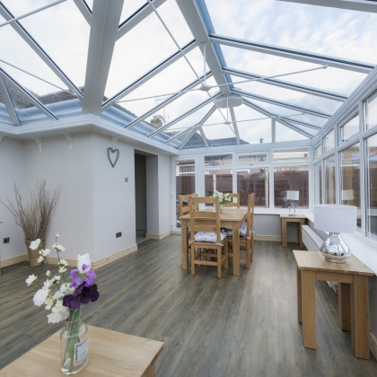 Inside view of a white conservatory with wooden furniture