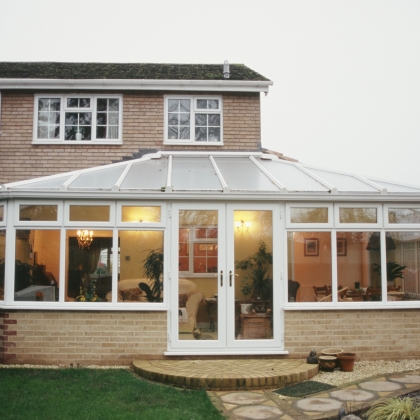 Glazed extension with the lights on in a garden