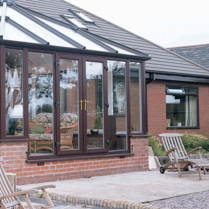 Rosewood glazed extension with wooden deckchairs in the garden