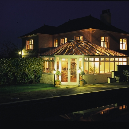 Night time view of a brightly lit glazed extension