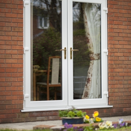 White PVCu doors in brick house with curtains