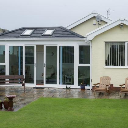Outside view of a conservatory with doors partially open and rainy outdoors